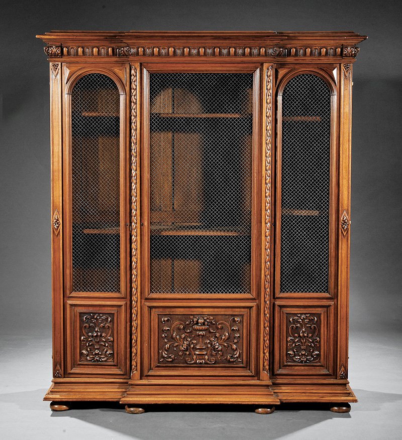 A Renaissance-Style Carved Walnut Bibliothèque: A Renaissance-Style Carved Walnut Bibliothèque, early 20th c., probably French, stepped egg and dart carved cornice, arched and rectangular grillwork doors, foliate carved stiles and panels, blocked 