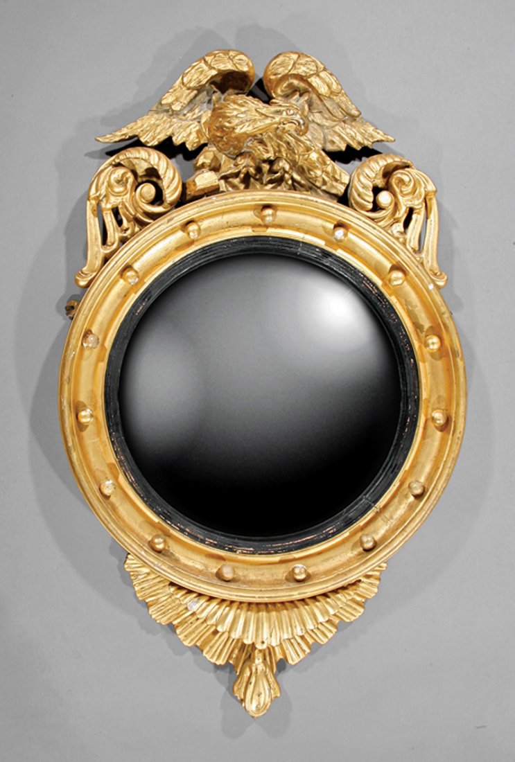 Carved Giltwood Bullseye Mirror: Good American or English Carved Giltwood Bullseye Mirror, early 19th c., surmounted by an eagle on rockwork, circular frame with spherules and ebonized rabbet, convex mirror plate, base with fan penda