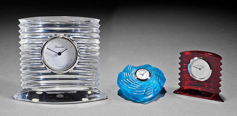 Three French Art Glass Table Clocks: Three French Art Glass Table Clocks, Lalique "St. Valentine", h. 1 3/4 in., and 2 Baccarat "Lalande", ruby and clear glass, h. 2 7/ 8 in. and 5 in. Provenance: Estate of Dr. Roger Hatchette, New Orlea