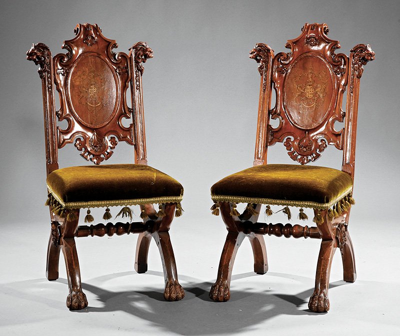 Pair of English Carved Mahogany Hall Chairs: Pair of English Carved Mahogany Hall Chairs, mid-19th c., back with polychromed achievement of arms, gothicized crest, lion's mask terminals, padded seats, curule legs centering a mask, paw feet Note: