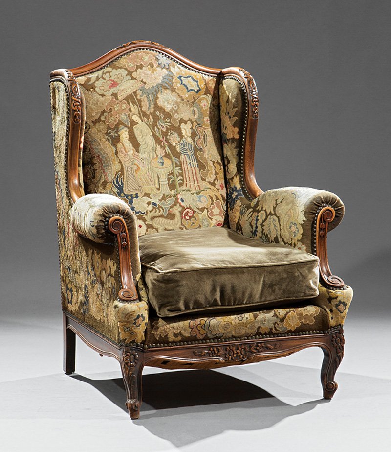French Walnut Bergere á Oreilles: French Walnut Bergere á Oreilles, 20th c., arched crest, cabochon carved winged sides, scrolled arms, floral carved seat rail, cabriole legs, scrolled toes. Provenance: Kevin Stone Antiques, New Orle