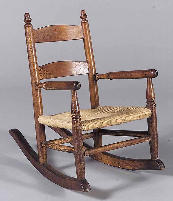 Antique American Child's Rocking Chair: An Antique American Child's Rocking Chair , 19th c., having finialed stiles turned arms, later rush seat, turned stiles, the shaped rocker connected by stretchers, height 20 1/2 in * NO RETURNS ARE AC