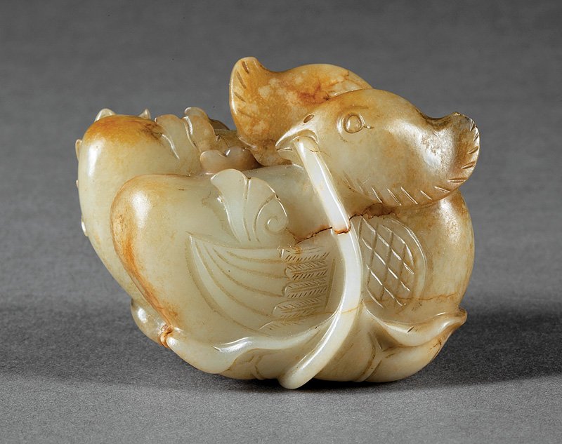 Chinese Celadon, Russet Jade Mandarin Duck Group: Chinese Celadon and Russet Jade Mandarin Duck Group, probably Ming Dynasty (1368-1644) or earlier, carved as a pair with heads turned to face one another atop a lotus leaf with stems and buds rising u