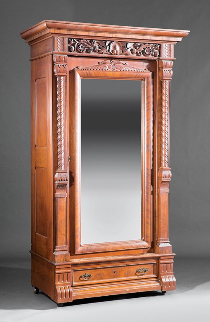 American Aesthetic Carved Walnut Armoire: American Aesthetic Carved Walnut Armoire, c. 1870, molded cornice, foliate frieze, columnar stiles, mirrored door, plinth drawer, casters, h. 92 in., w. 45 in., d. 27 in