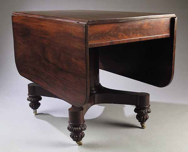 Mahogany Drop-Leaf Library Table, New York, manne: An American Classical Mahogany Drop-Leaf Library Table , early 19th c., New York, in the manner of Duncan Phyfe, the top above a crotch veneered and rosewood banded skirt, the tapered circular stem co