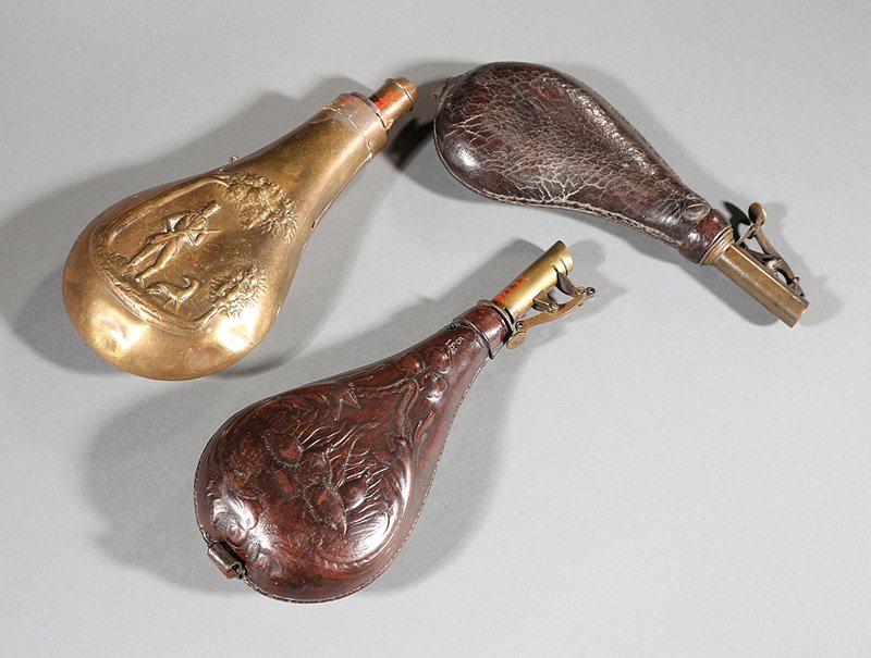 Three American or English Powder Flasks: Three American or English Powder Flasks, 19th c., two leather, one with quail; the other brass with a hunter and dog, largest h. 9 in. Provenance: Gaspar Cusachs, entrepreneur, historian and collector