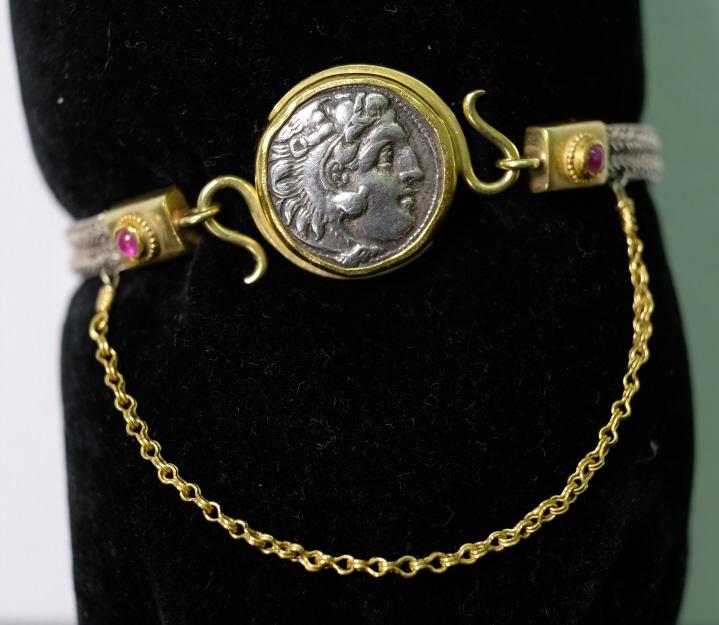 22K Gold Greek Hellenistic Drachm Bracelet: Fine Ancient Silver Quadruple loop-in-loop bracelet with the coin set in a 22 Karat Gold setting with Natural Rubies in a granulated gold rosette setting. The safety chain is also made of 22 Karat Gol
