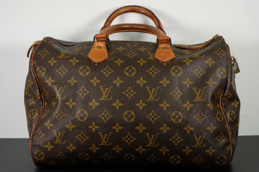 Louis Vuitton Monogram Speedy 35: This stylish handbag is crafted of traditional Louis Vuitton monogram on coated canvas. The bag features vachetta cowhide leather trim, and rolled top handles with polished brass hardware. The top zip