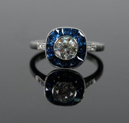 Vintage Style Platinum Diamond & Sapphire Ring: Vintage style diamond and sapphire ladies ring set in platinum and having a 0.70 carat total weight center faceted diamond (color: H, clarity: SI1) bordered with 0.70 carat total weight faceted sapphi