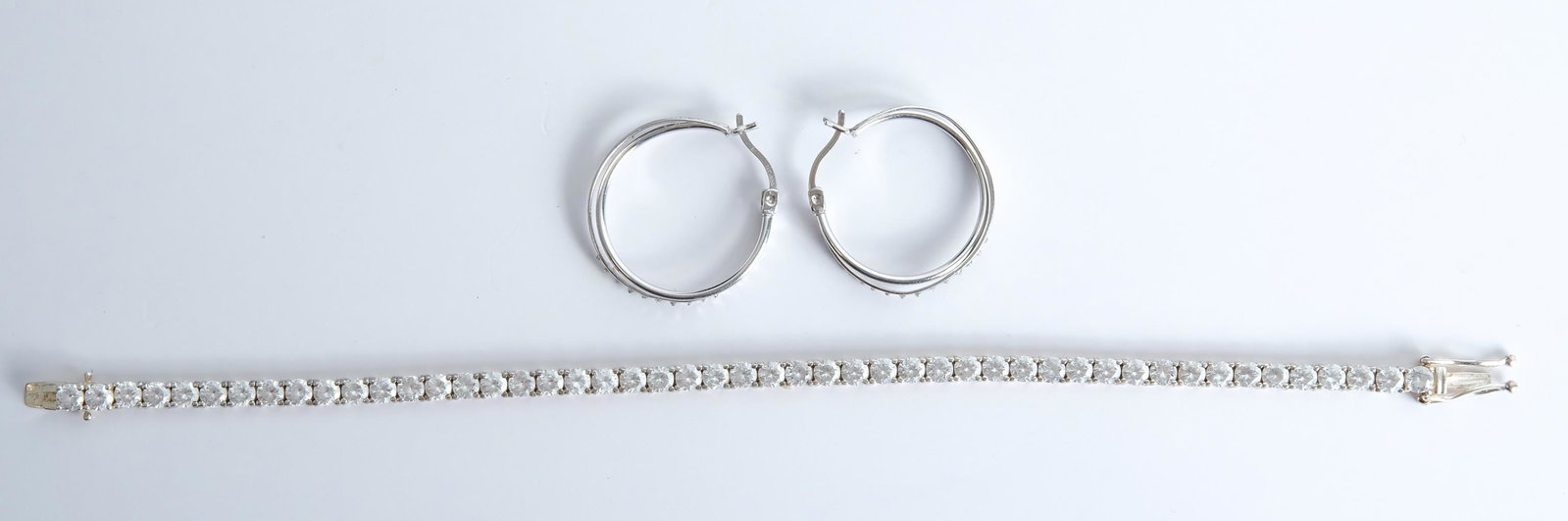 Sterling Silver Tennis Bracelet w/Earrings: Sterling silver tennis bracelet with faux diamonds along with a pair of sterling hoop earrings. Bracelet and earrings stamped 925. Approx. length of bracelet 7.5", hoops 1" diameter.