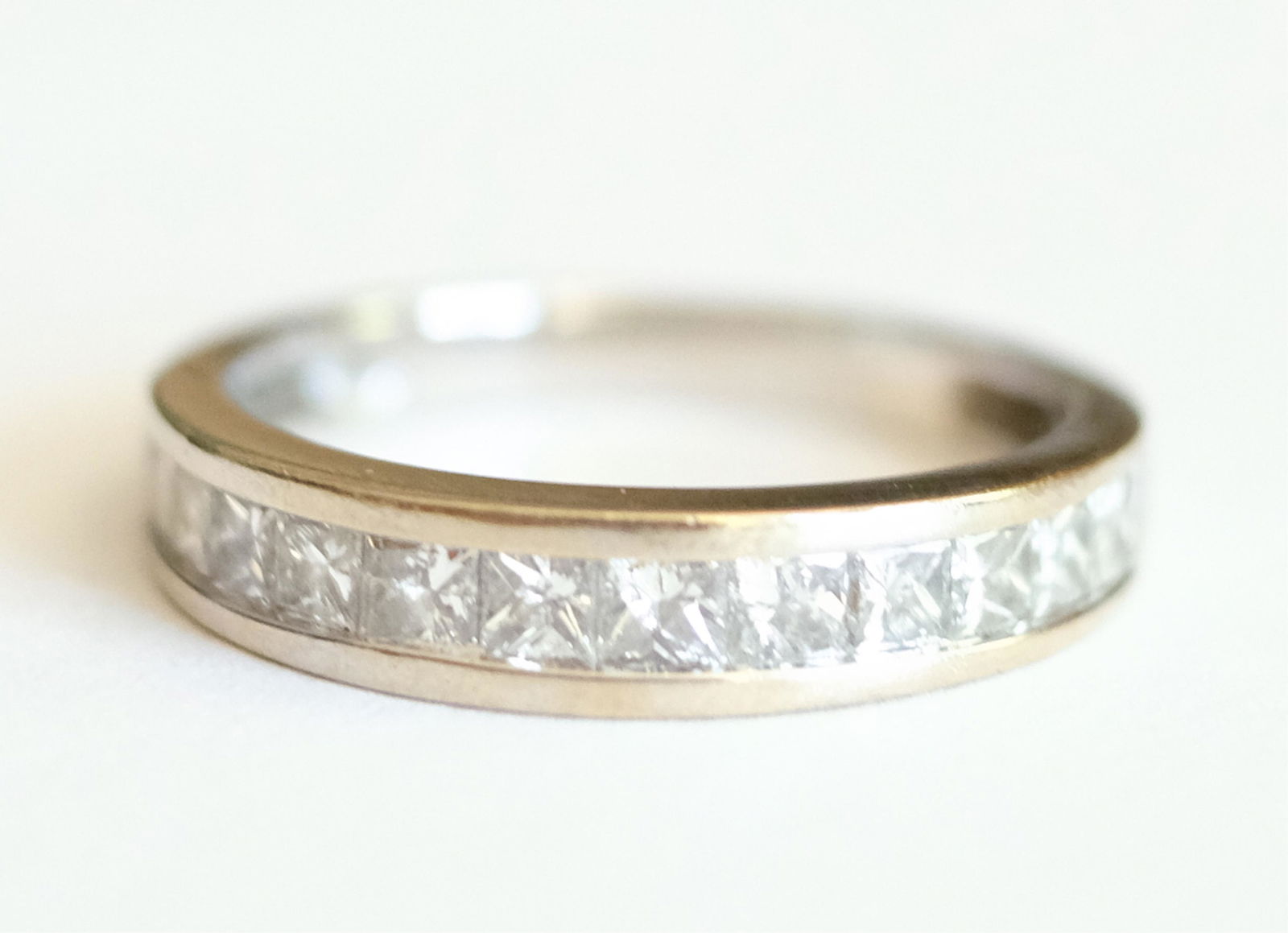 14K White Gold Diamond Wedding Band: 14K white gold wedding band having twelve channel set diamonds. Size 7.5. Stamped 14K WG and Oj 1.00. Approx. overall weight 3.09 grams.