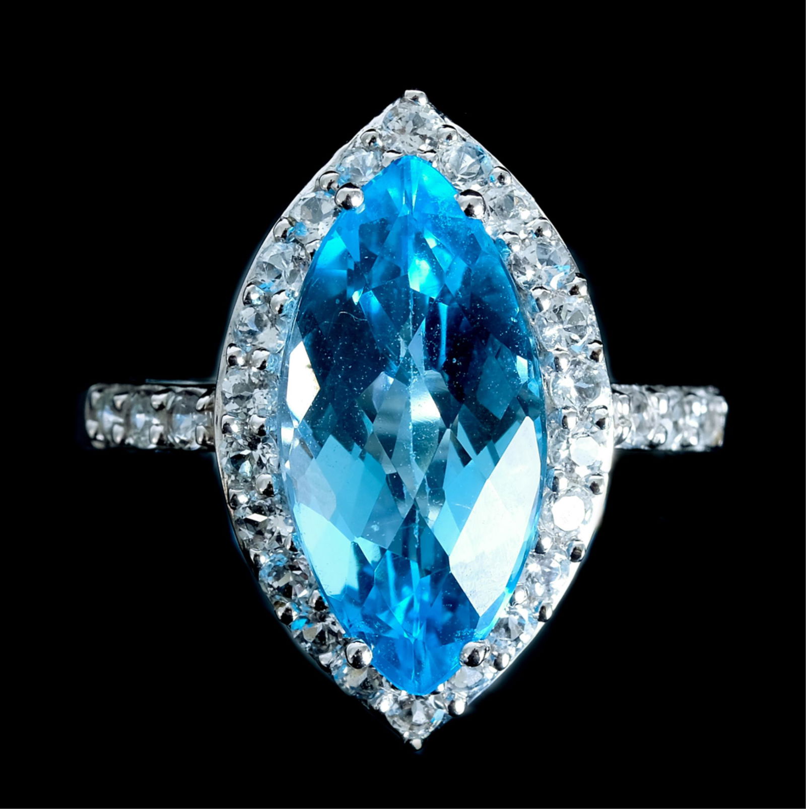 10k White Gold Blue Topaz White Sapphire Ring: 10k white gold ring with marquise shaped faceted blue topaz within a white sapphire halo. Ring size 71/2. Stamped 10k. Approx. overall weight 4.10 grams.