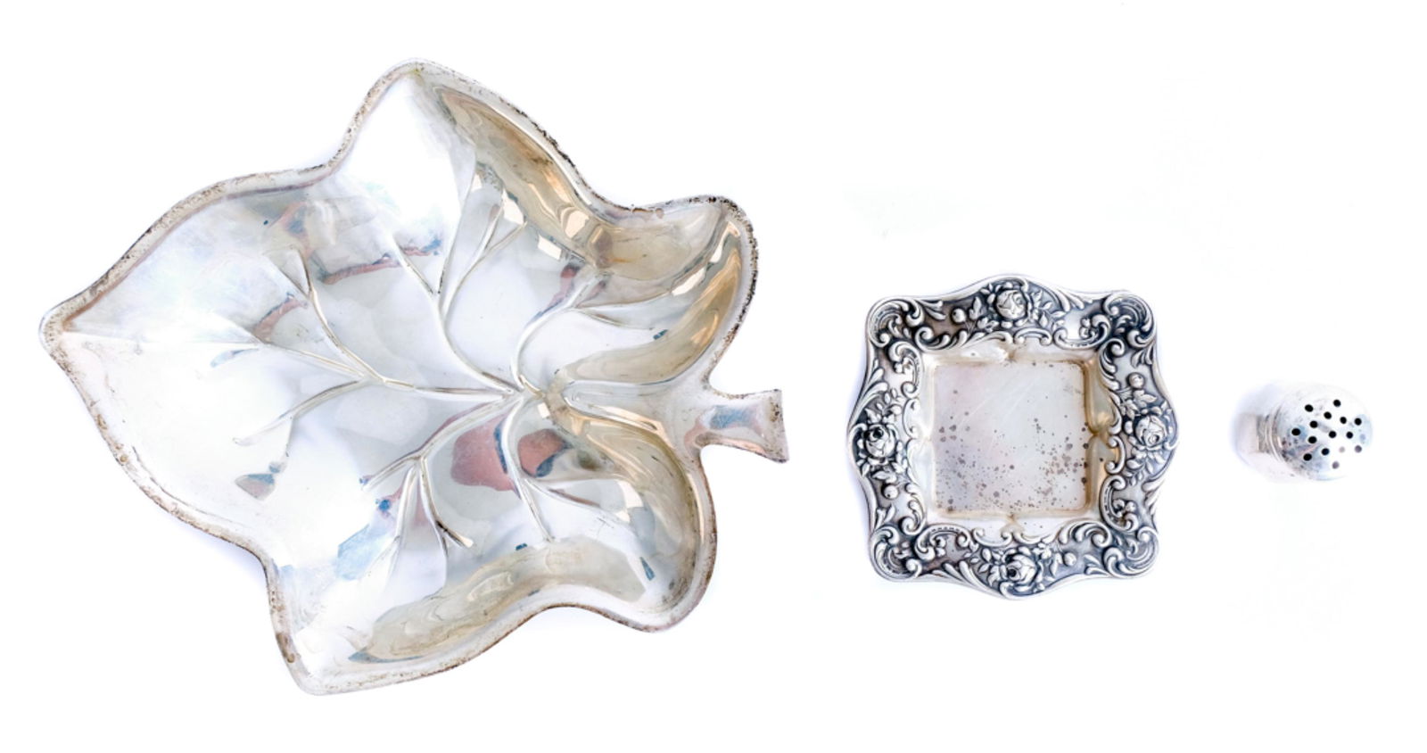 Three American Sterling Silver Table Accessories: Group of three American sterling silver table accessories comprising a Gorham butter pat dish (3.25"); Webster salt shaker (1.25") and a Hunt Silver Company leaf shaped dish (1" x 7.5" x 6.25"). Appro