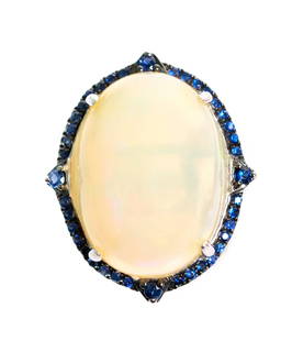 14k WG 8.64 Opal & Blue Sapphire Ring, Size 7: 14k white gold ring set with a 8.64 Opal within a border of 0.63ct blue sapphire accents. Ring size 7. Hallmarked 14k SNJ CN. Approx. overall weight 6.9 grams