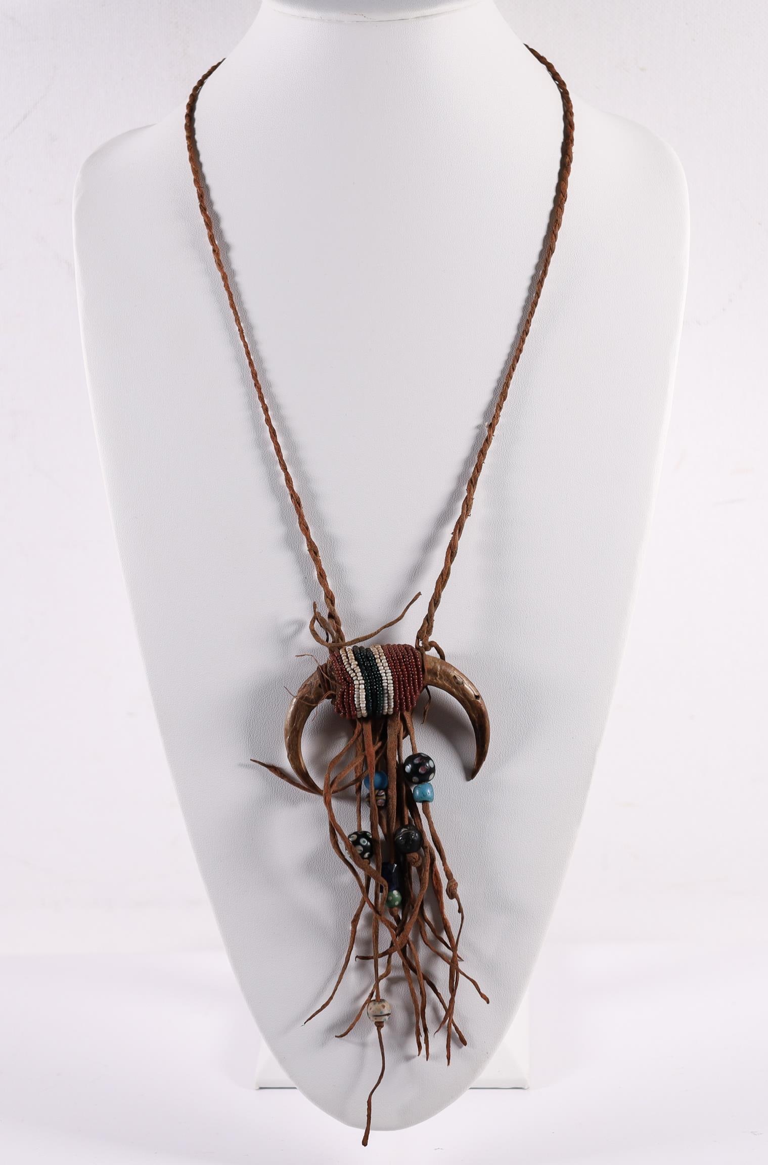 SIOUX TRADING NECKLACE WITH BONE ACCENT: Sioux trading necklace with bone accent. Decorative red,green,white micro beaded bone centerpiece adorned with Czech chevron glass beads and leather straps. Measurements Length: 12 IN.