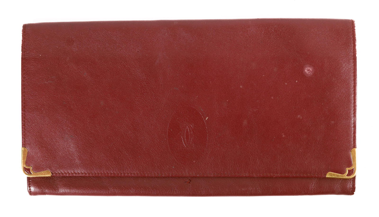 LES MUST DE CARTIER VINTAGE CONTINENTAL WALLET: A vintage burgundy leather Cartier wallet with gold-tone hardware, Logo Jacquard lining, and four interior pockets with card slots. Measurements: Height: 4 IN. / 10 CM. Width: 7.5 IN. / 19 CM. Depth: