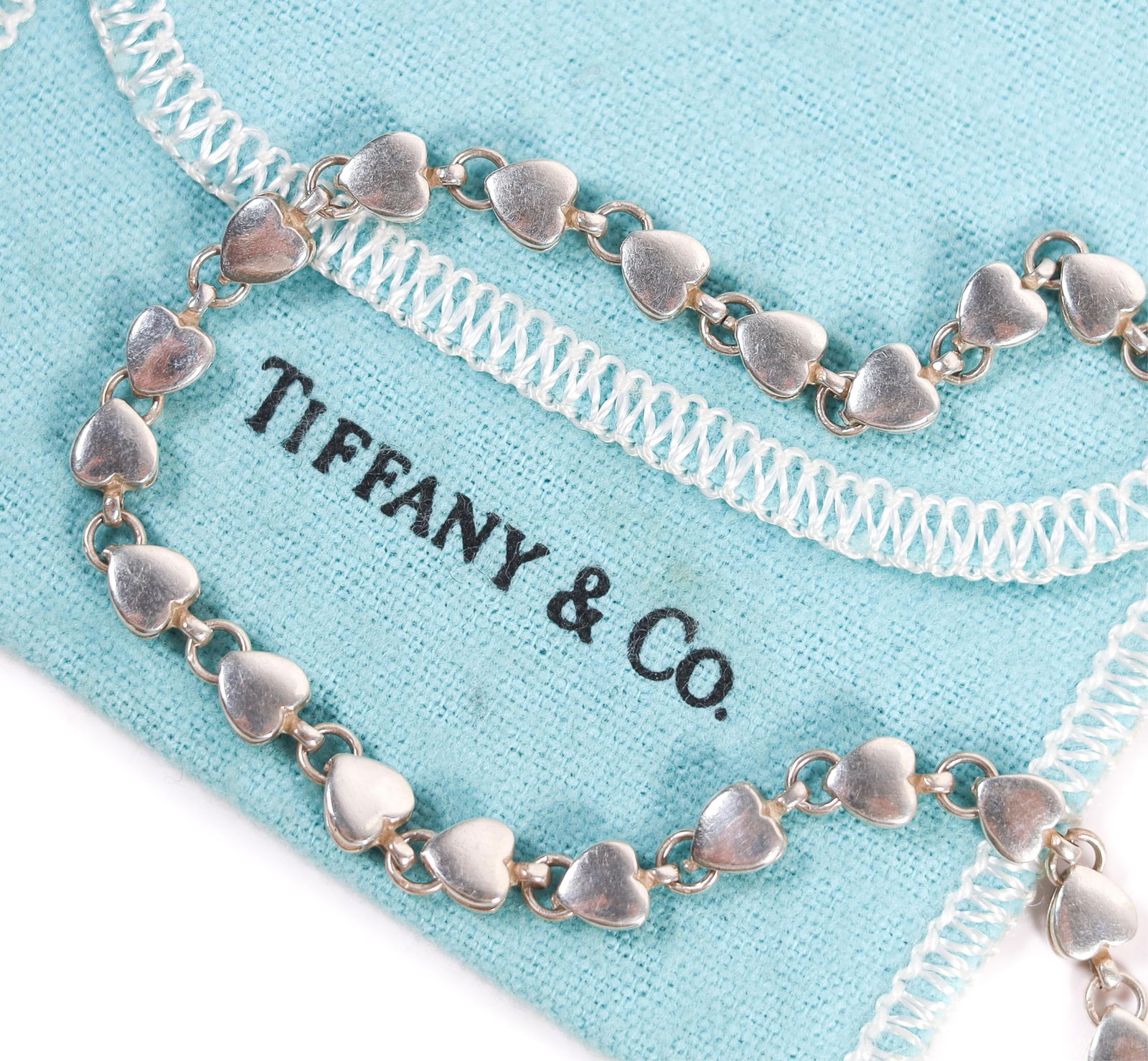 VINTAGE TIFFANY & CO HEART LINK CHAIN NECKLACE 925: A vintage Tiffany & Co. necklace composed of beautiful ongoing links of sterling silver hearts. Comes with a Tiffany storage bag. Stamped 925 on the clasp. Details and measurements: Necklace length: 1