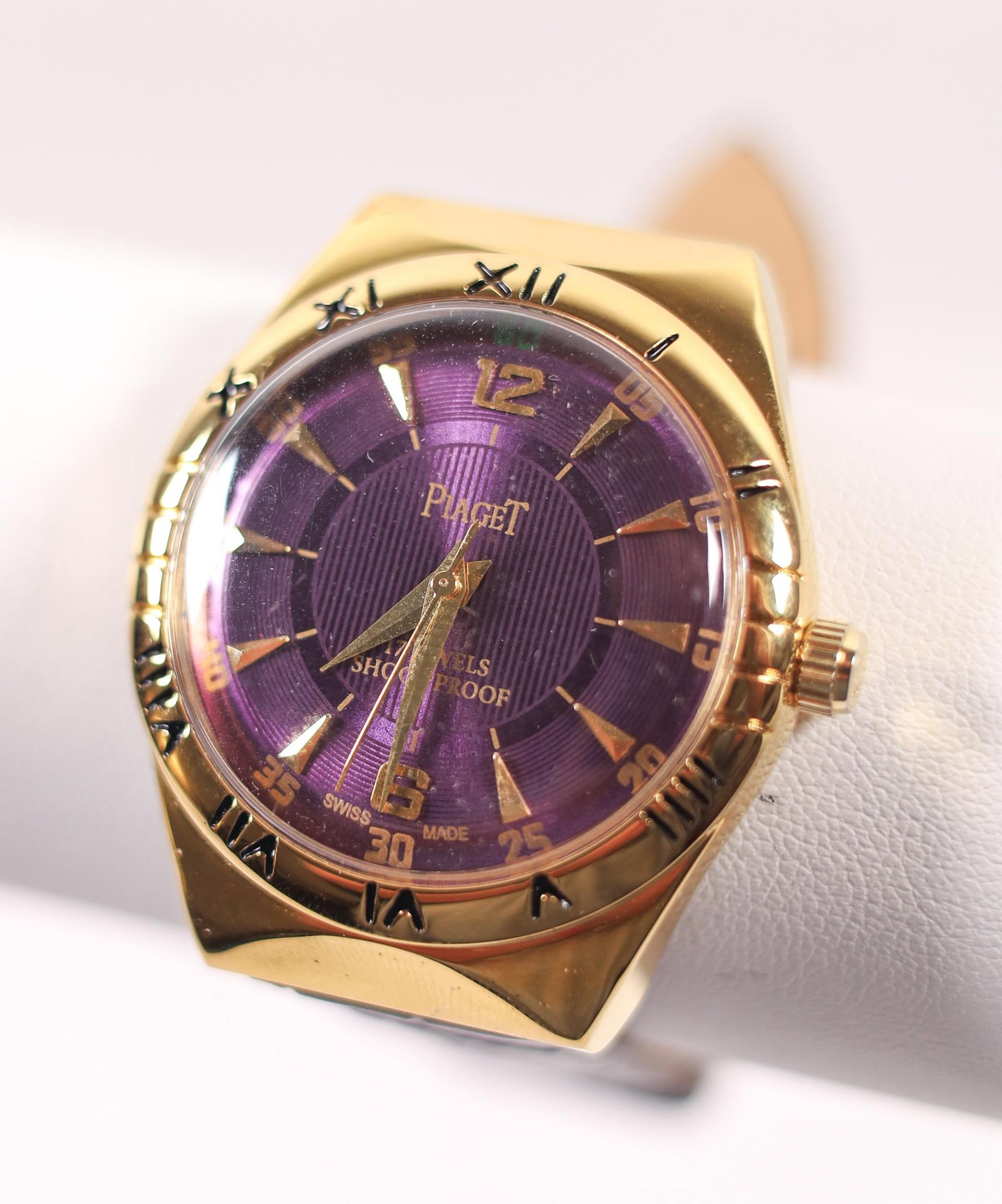PIAGET 17 JEWELS SHOCKPROOF MANUAL EGP WATCH 37MM: A Piaget 17 Jewels shockproof manual gold-plated watch. It features a purple dial, a black leather band, and a gold-plated bezel. Details and measurements: Diameter: 37 MM.