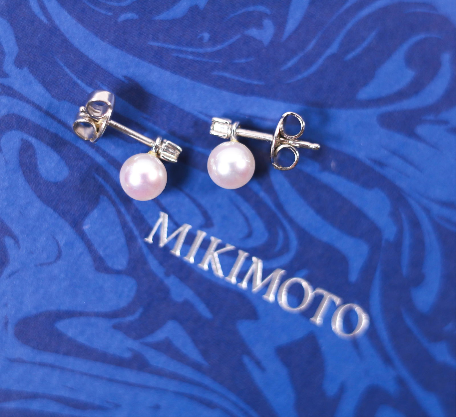 MIKIMOTO 18KWG 5.5MM PEARL DIA. STUD EARRINGS: A gorgeous pair of Mikimoto 18-karat white gold 5.5 pearl earrings accented by a round-cut diamond. Stamped Mikimoto, K18, on the back of each earring. Details and measurements: Total weight: 1.6 G.