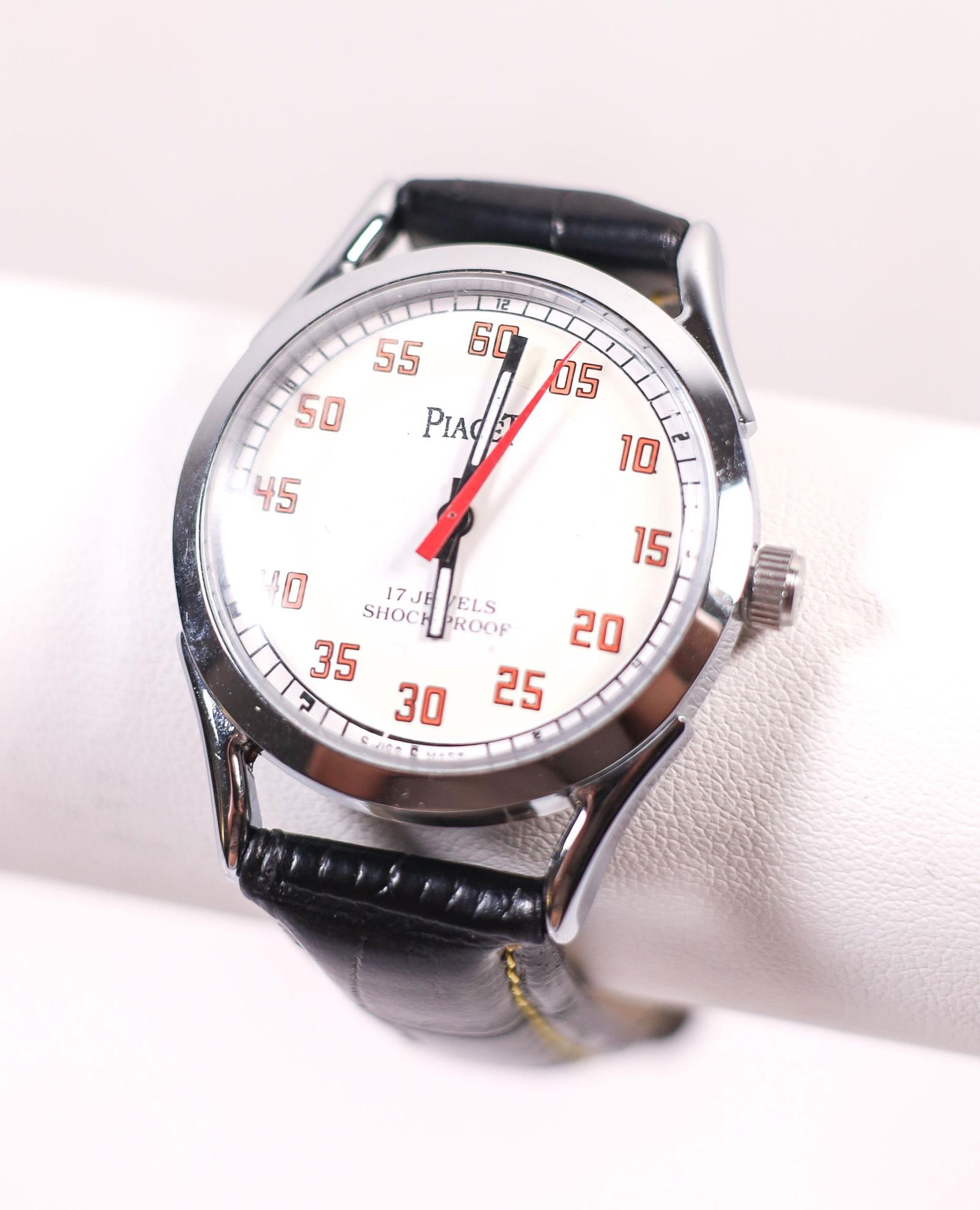 PIAGET 17 JEWELS SHOCKPROOF MANUAL WATCH: A Piaget 17 Jewels shockproof manual watch in excellent condition. This watch features a white dial, a stainless steel case, and a black leather band. Details and measurements: Diameter: 36 MM.