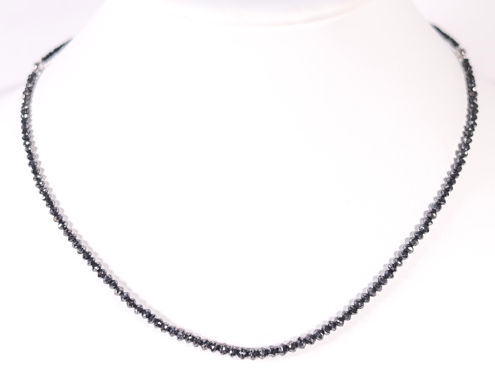18KWG 30CT BLACK DIAMOND NECKLACE: An 18-karat white gold 30-karat black diamond faceted necklace. Stamped K18WG, 30.00, on the necklace's clasp. Details and measurements: Necklace length: 17.5 IN, Weight: 8.0 G.