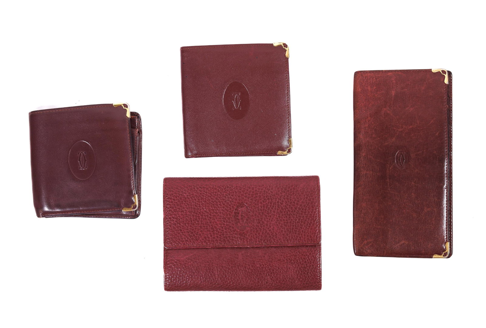 LOT OF 4 CARTIER BURGUNDY WALLETS: Two Cartier bi-fold wallets and two Cartier long wallets. These items are grouped because they have significant wear.