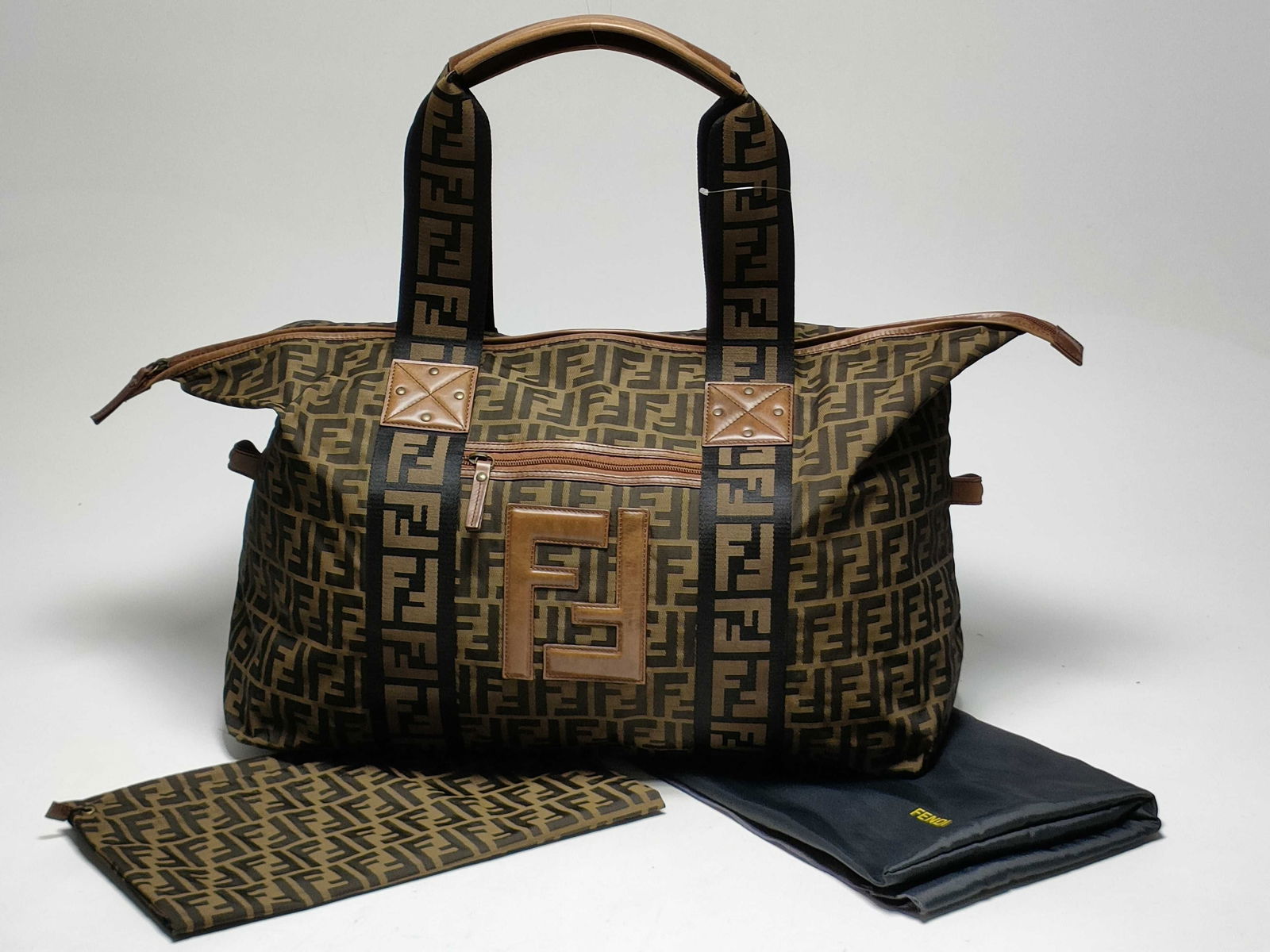 Fendi Zucca Canvas Boston Bag: Authentic fendi boston bag featuring brown zucca monogram canvas with tan leather trim and top handles. double zip closure, fabric interior with fendi label, and matching zucca pouch included. exterio