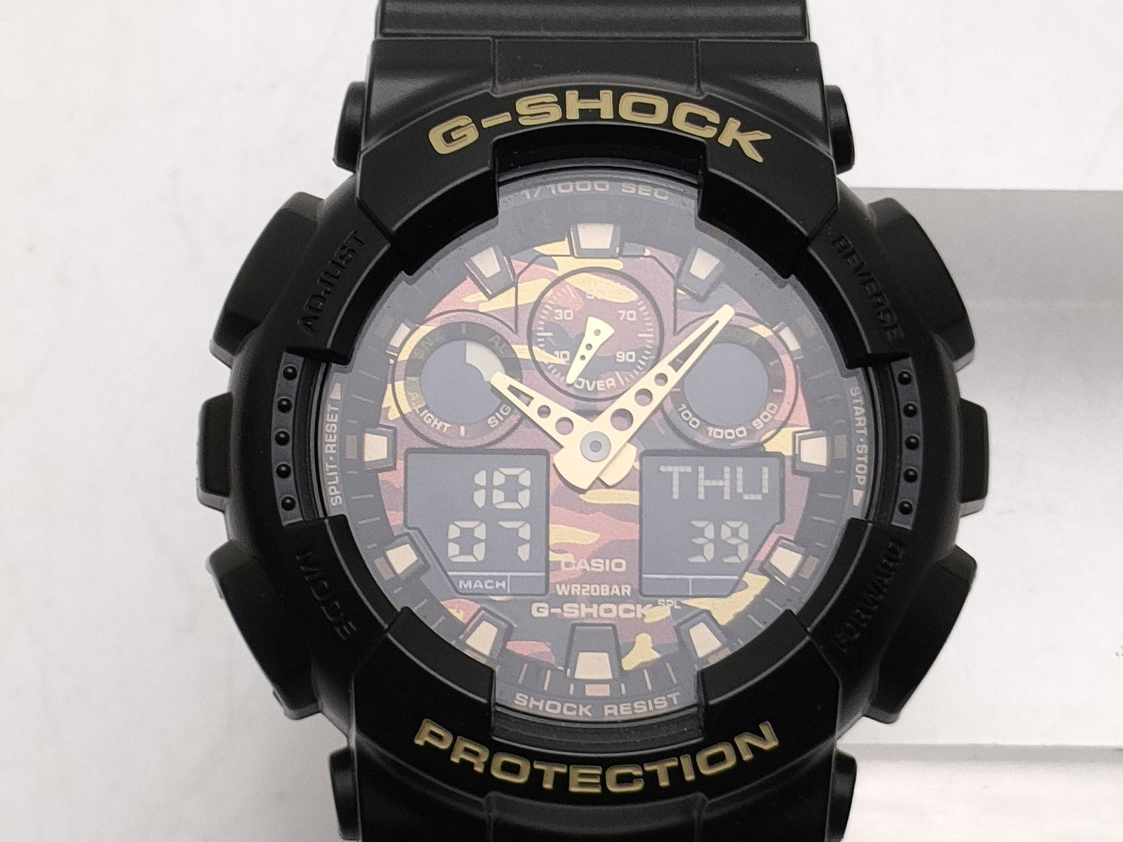 Casio G-Shock GA-100CF 5081 Black Camo Dial Men’s Watch: Casio g-shock men’s watch, authentic. black resin case with large round face featuring camouflage-patterned dial. gold-tone digital and analog combination display with luminous hands and markers. te
