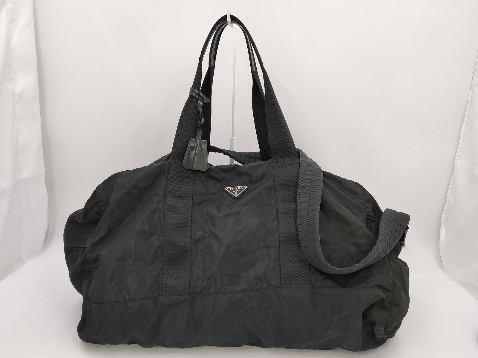 Prada Black Nylon 2-Way Boston Bag: Prada Boston bag having a soft rectangular duffel form with double top handles and detachable shoulder strap. Featuring black nylon exterior with tonal stitching and triangular metal Prada logo plaque