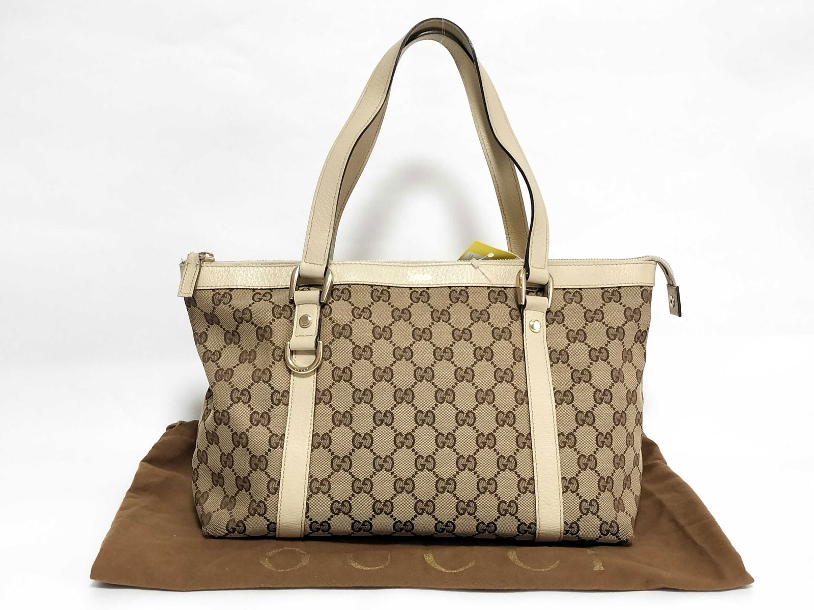 Gucci GG Canvas Abbey tote bag with beige leather trim: Authentic Gucci tote bag having brown GG canvas featuring cream leather trim and rolled leather handles. 