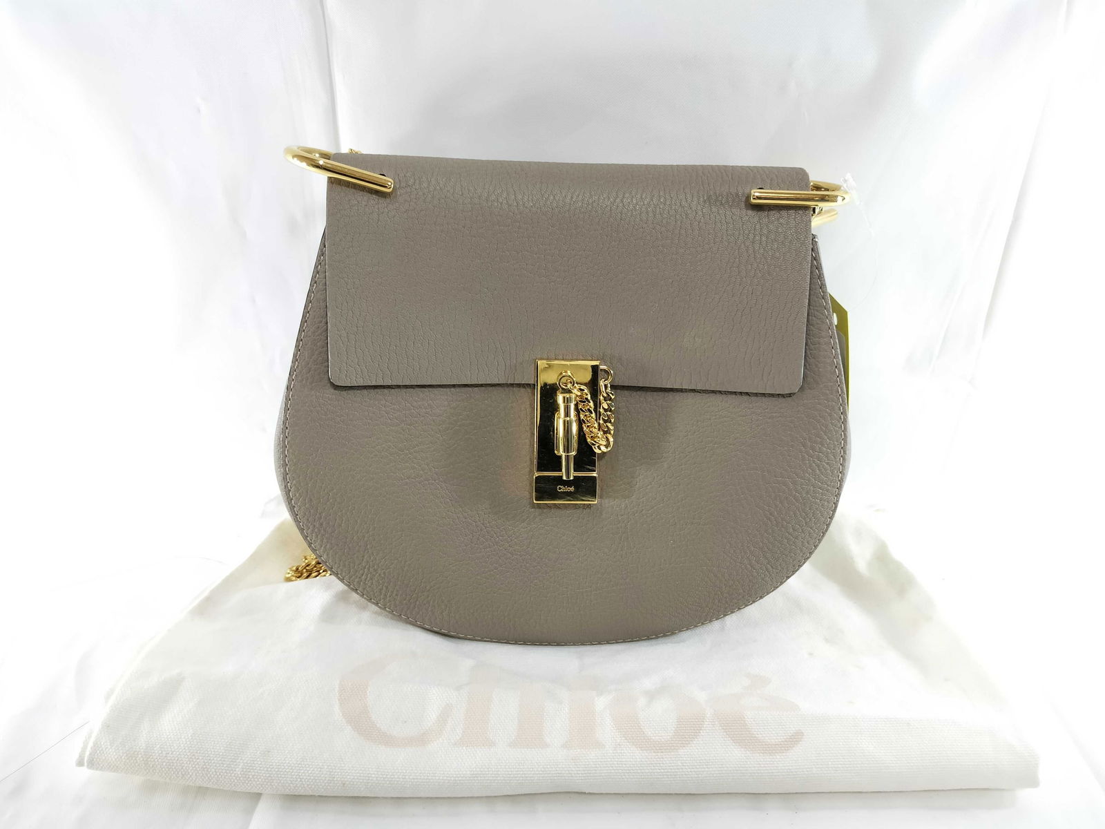 Chloé Beige Leather Chain Shoulder Bag with Dust Bag: Authentic Chloé Beige leather shoulder bag having a rounded silhouette featuring grained leather, a front flap, and a gold-tone chain strap. Front flap featuring a gold-tone bar detail and a ha