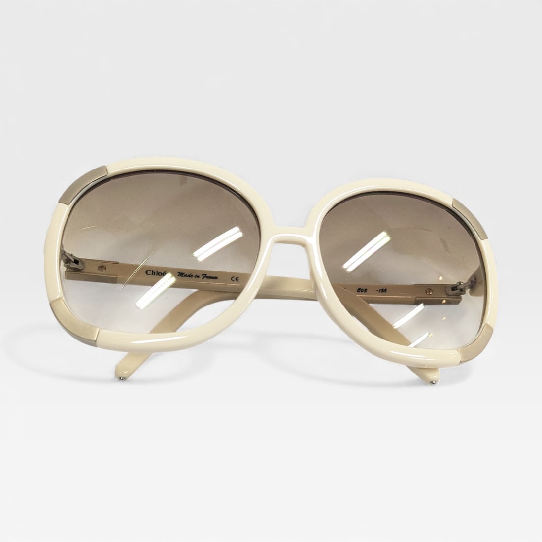 Chloé White and Silver Oversized Sunglasses: Authentic Chloé White and Silver Oversized Sunglasses. Banded silver metal over white acetate frames and gradient smoky grey lenses.