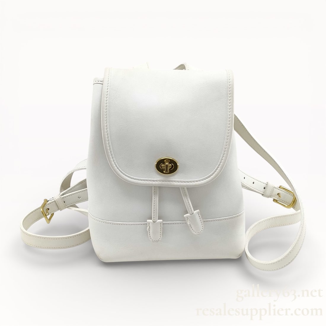 Coach White Leather Turnlock Rucksack Backpack: Coach rucksack having smooth white leather construction with structured silhouette. Flap front secured with a gold-tone turnlock closure. Drawstring top opening beneath the flap. Adjustable leather sh