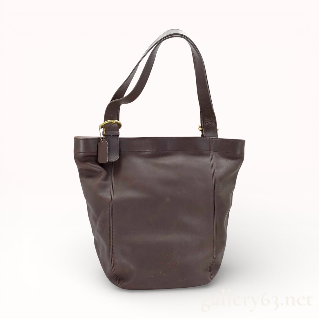 Coach Glove-Tanned Leather Tote Bag: Coach brown leather tote bag having a structured open-top form and smooth leather exterior. Bag featuring dual shoulder straps with adjustable buckle detail and gold-tone hardware. Interior having fab