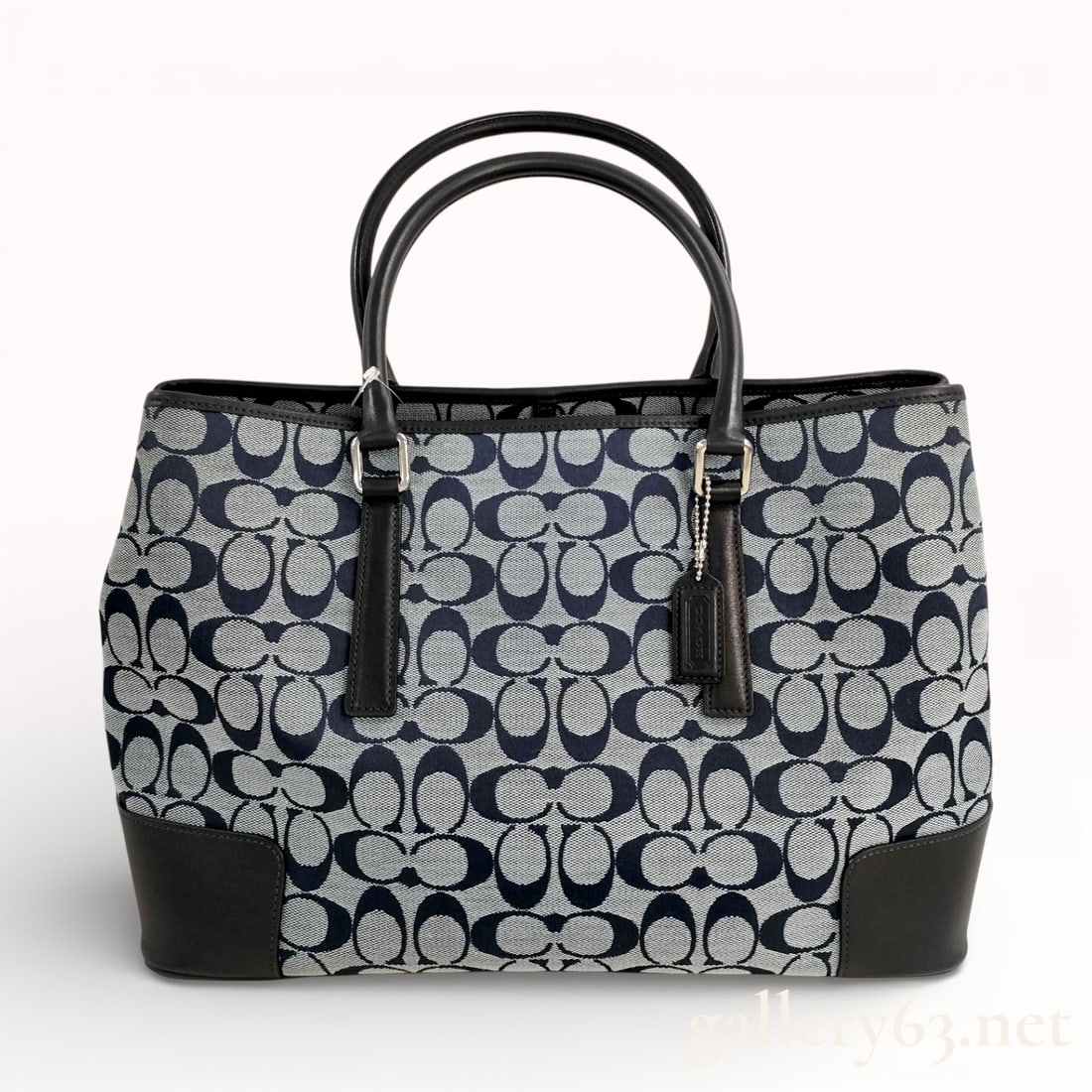 Coach Signature Navy and Black Canvas and Leather Tote Bag: Authentic Coach signature tote bag having navy and black canvas exterior with repeating “C” monogram pattern. Bag featuring black leather trim at the base, corners, and handles, and silver-ton