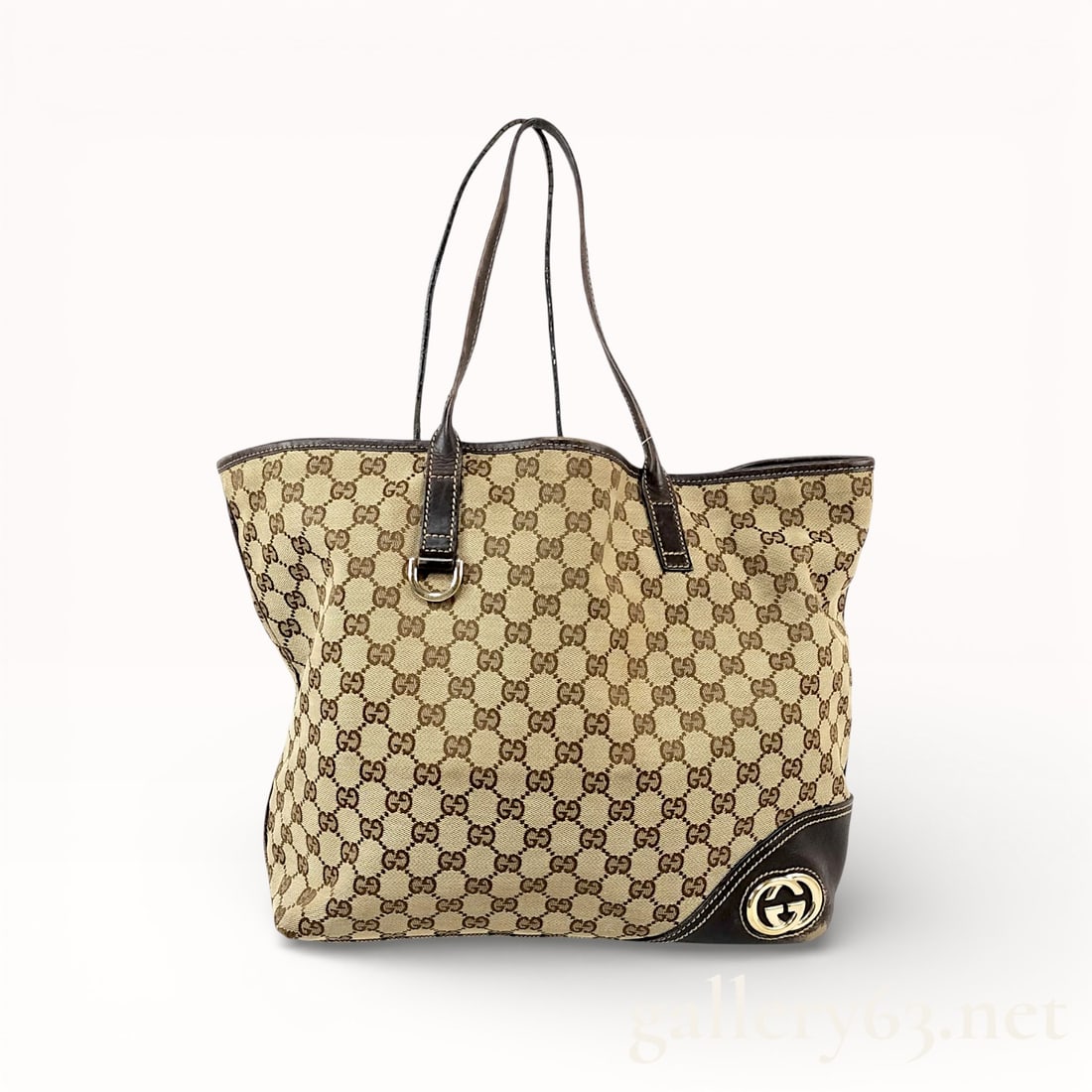Gucci New Britt Tote Bag in Dark Brown Leather & Neutrals Canvas: Authentic Gucci tote bag constructed of beige GG monogram canvas. Bag having dark brown leather trim and matching leather shoulder straps. Front corner set with a round Gucci logo medallion in gold-to