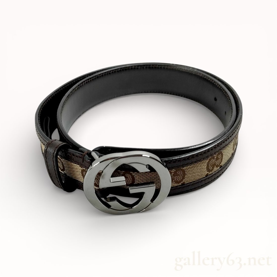 Gucci GG Canvas and Leather Belt 114874: Authentic Gucci belt featuring GG monogram canvas set within black leather trim and backing. Interlocking GG buckle executed in silver-tone metal with a polished finish. Adjustable belt construction w