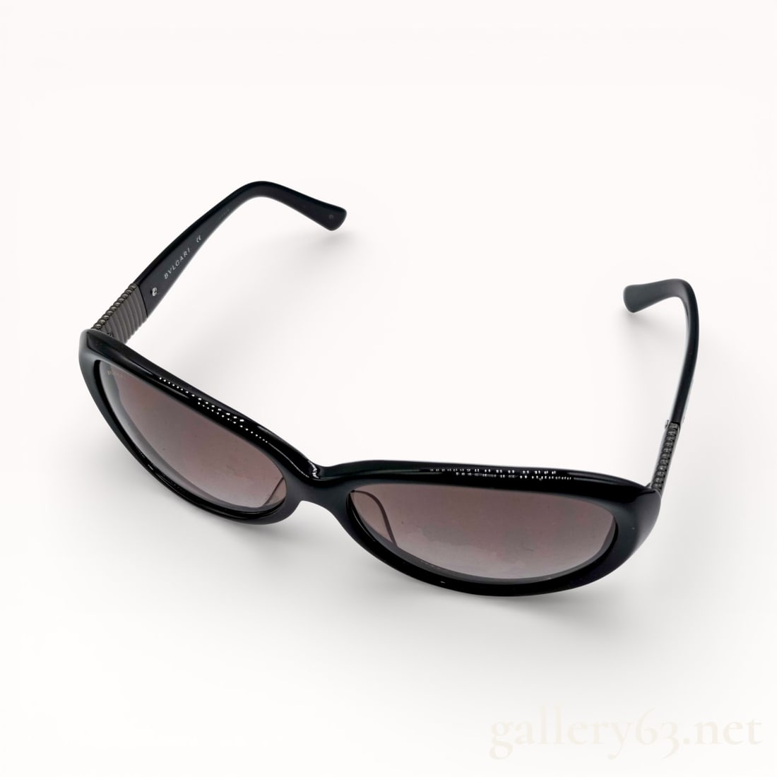 Bvlgari 8062 Black Acetate Sunglasses: Authentic Bvlgari sunglasses featuring a slim oval frame crafted in glossy black acetate. Dark tinted lenses set within softly curved rims. Tapered arms extending from the frame with subtle textured d