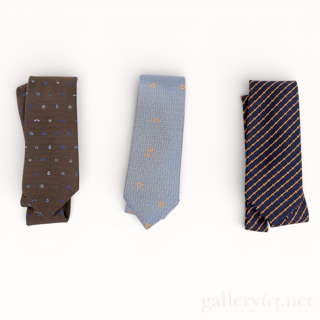 Hermès All-Over Pattern Silk Tie Set of Three: Authentic Hermès tie set featuring three silk neckties, each woven with an all-over pattern. One tie presented in a brown ground with small repeating motifs, one tie presented in a light blue ground
