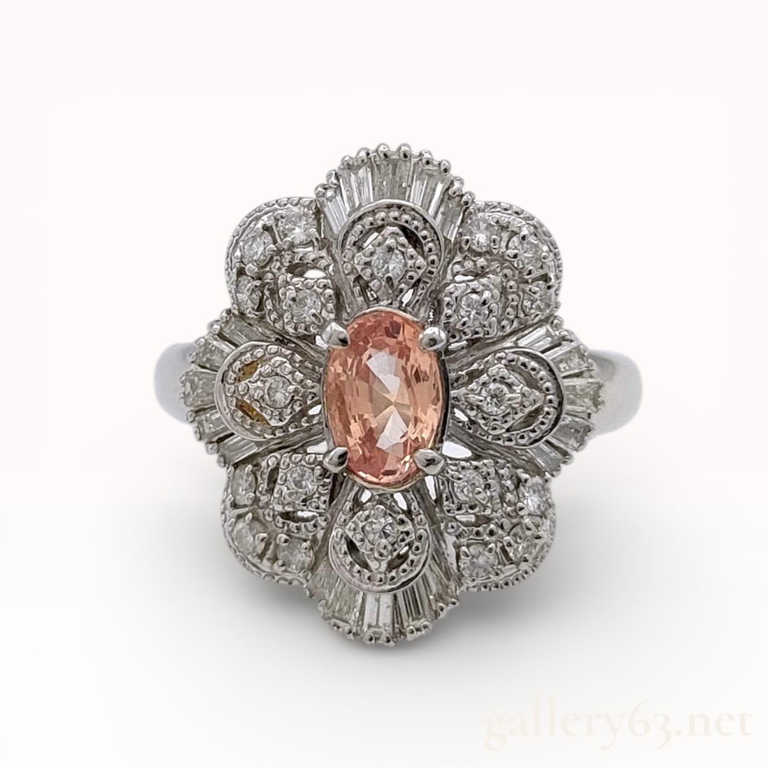 Platinum and Diamond Floral Ring with Oval Pink Sapphire: Authentic Platinum ring having an oval pink sapphire center stone weighing approximately 0.64 carats. Surrounding design arranged in a floral motif, set with round and baguette-cut diamonds totaling a