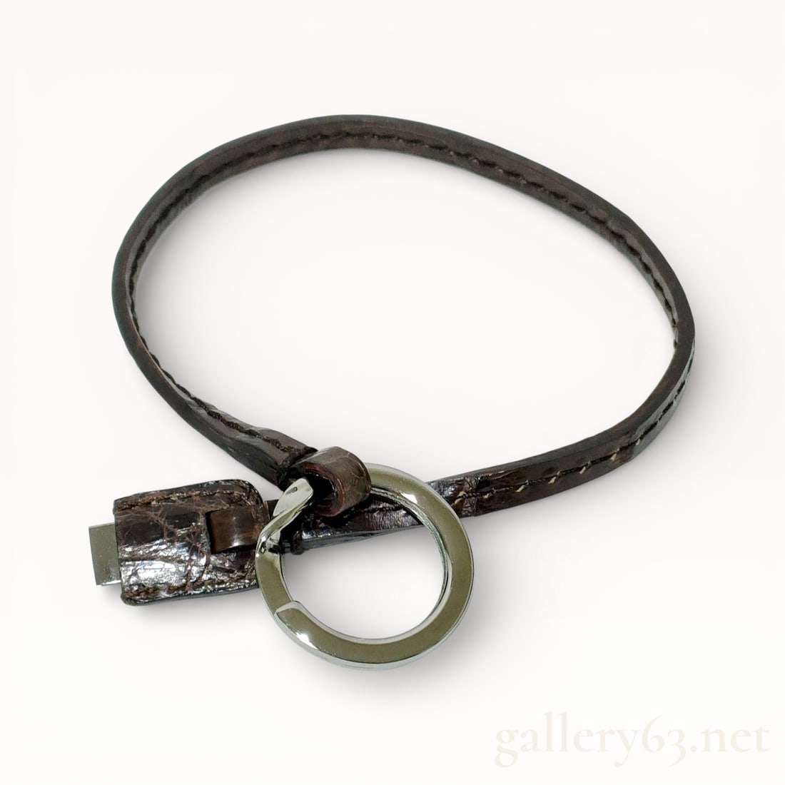 Gucci Crocodile-Embossed Leather Keychain/Keyring: Authentic Gucci keychain featuring a dark brown leather strap with a crocodile-embossed surface texture. Circular metal key ring attached at one end, finished in a silver-tone surface. Strap forming