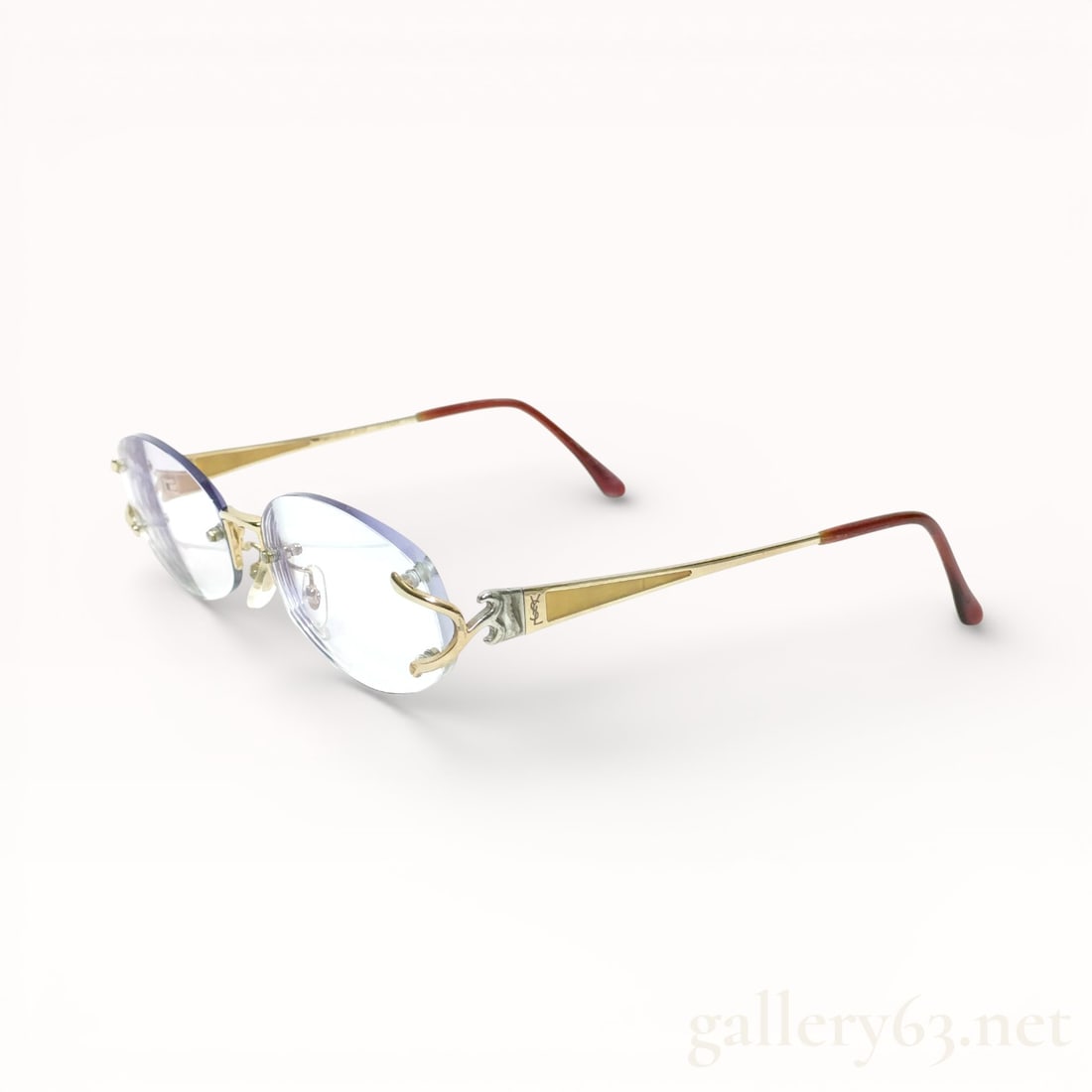Yves Saint Laurent Metal Frame Eyeglasses: Authentic Yves Saint Laurent eyeglasses featuring a gold-tone metal frame with an oval lens shape. Clear lenses set within slim wire rims. Adjustable clear nose pads mounted on metal arms. Temples ext