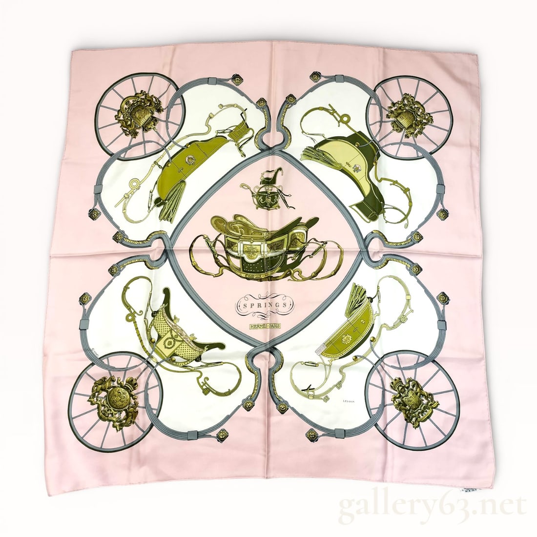 Hermès Springs Silk Carré Scarf: Hermès silk carré scarf featuring the Springs design, rendered in soft pink with olive green, gray, and cream accents. Symmetrical composition presents horse-drawn carriage elements, reins, and whee