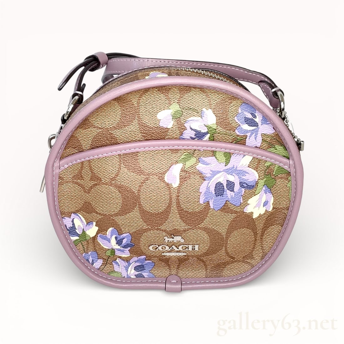 Coach Signature Flower Round Shoulder Bag: Coach shoulder bag having a round silhouette constructed in signature coated canvas with an allover C motif. Front panel featuring floral print accents in lavender, blue, and green tones. Trim and pip