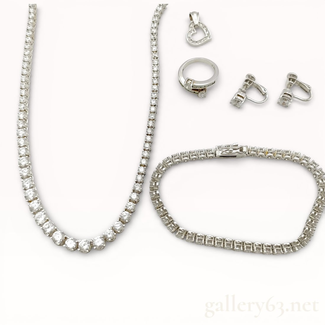 Sterling Silver Transparent Stone Tennis Necklace, Bracelet, Ring, Earrings and Charm Pendant: Authentic 925 sterling silver and brilliant cut colorless transparent stone tennis necklace, tennis bracelet, ring, screw back earrings, and heart shaped charm pendant. 47.3 grams total weight. 