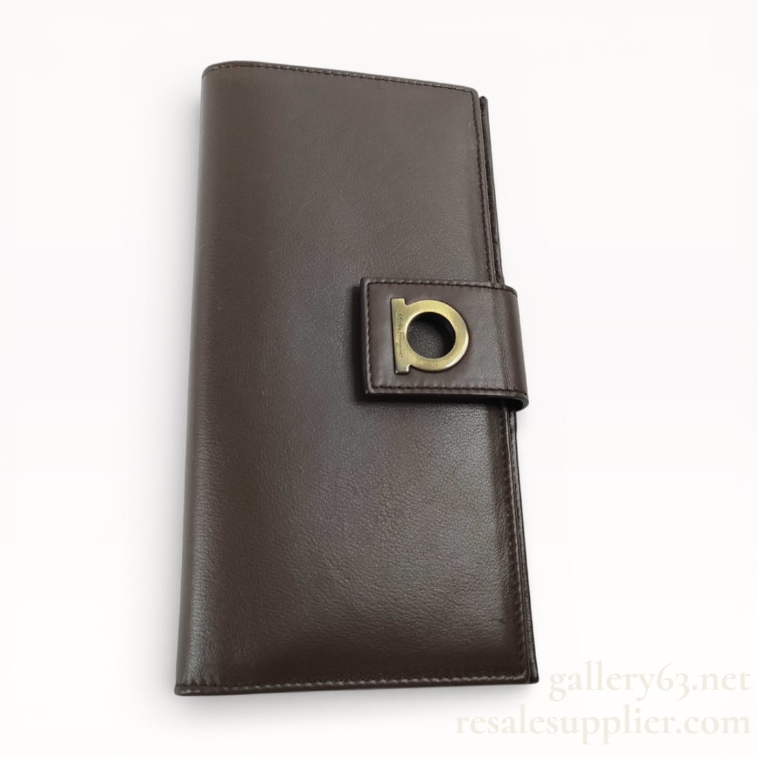 Salvatore Ferragamo Gancini Bi-Fold Long Leather Wallet - Excellent Condition: Salvatore Ferragamo long wallet having smooth brown leather construction. Bi-fold design secured with a strap closure set with a gold-tone Gancini logo accent. Elongated rectangular profile with