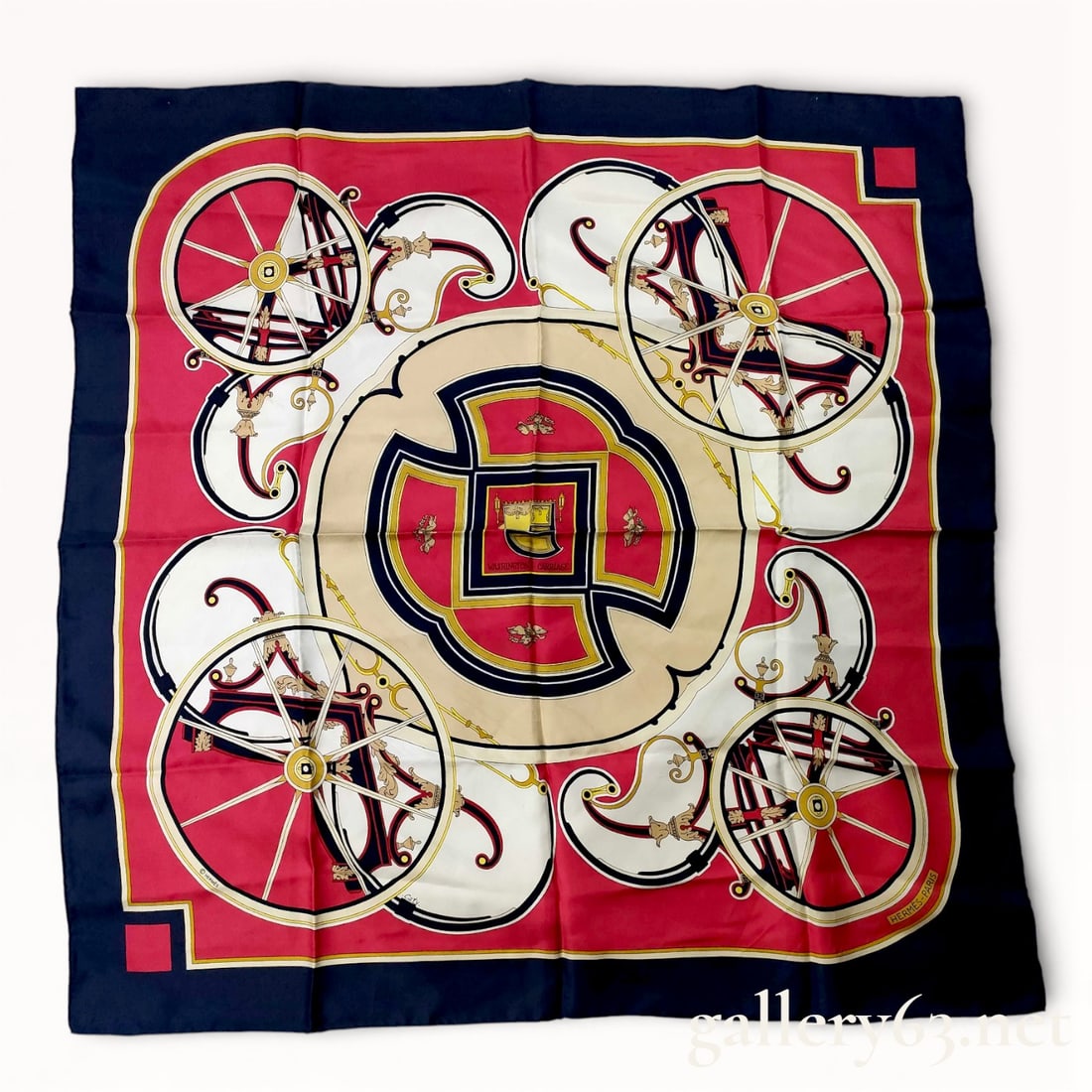 Hermès Carriage Silk Carré Scarf 90cm: Hermès silk carré scarf featuring a carriage-themed design, rendered in red, cream, navy, and gold tones. Symmetrical composition presents four carriage wheels arranged around a central medallion,