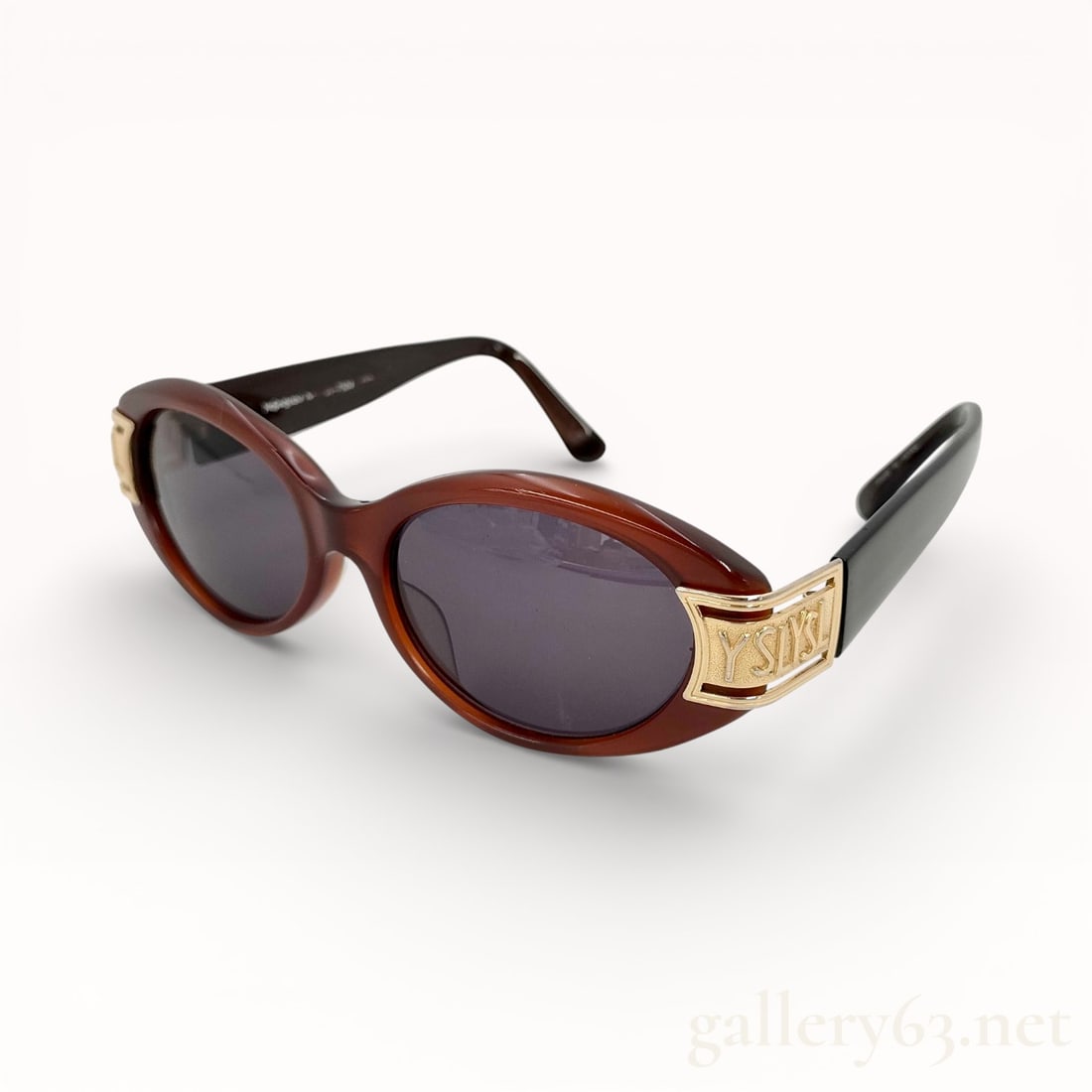 Vintage Yves Saint Laurent 31-7504 sunglasses in brown and gold: Authentic Yves Saint Laurent sunglasses featuring a brown translucent plastic frame having an oval lens shape. Dark tinted lenses set within a softly contoured front. Temples accented with gold-tone Y