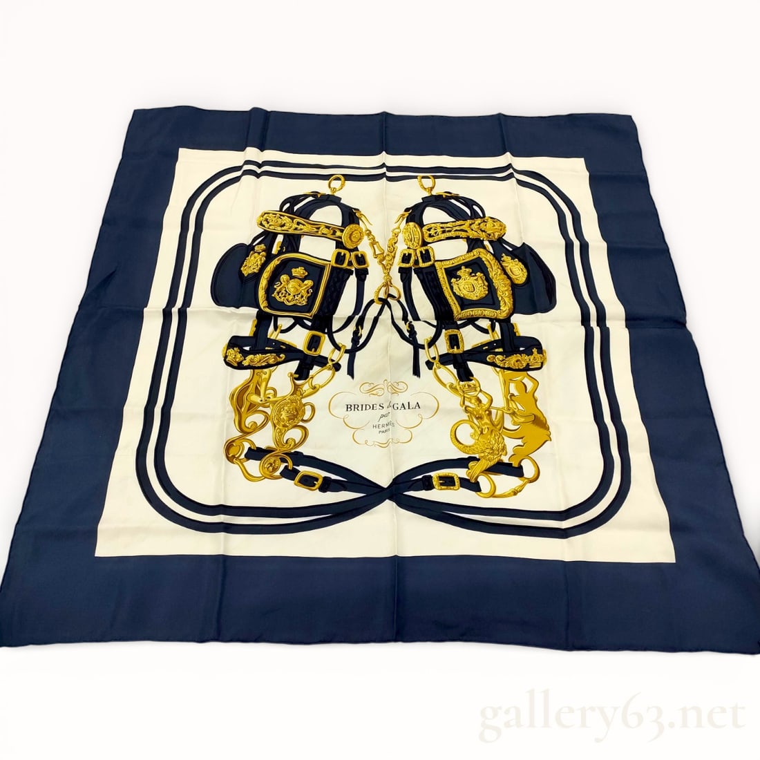 Hermès Brides de Gala Silk Carré 90 Scarf: Hermès silk carré 90 scarf featuring the iconic Brides de Gala design, rendered in navy, cream, and gold tones. Central motif presents ceremonial horse bridles and harness elements arranged