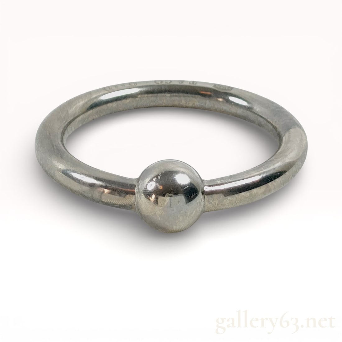 Tiffany & Co. Sterling Silver Baby Rattle 13cm: Authentic Tiffany & Co. baby rattle executed in sterling silver. The design presents a continuous circular form centered by a polished spherical element, creating a restrained and sculptural profi